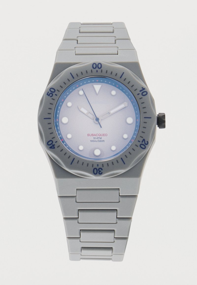 Γκρι ρολόι χειρός με στρογγυλό καντράν, λευκούς δείκτες ώρας, μπλε στεφάνη και γκρι μεταλλικό λουράκι με κρίκους, δείχνοντας ώρα 10:09:59.