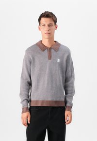 Knit sweater with a brown ribbed collar and hem, featuring a textured pattern in gray with a zip at the collar and a small logo detail.