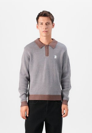 Knit sweater with a brown ribbed collar and hem, featuring a textured pattern in gray with a zip at the collar and a small logo detail.
