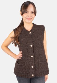 Braune, gestrickte Weste mit strukturiertem Finish, ausgestattet mit einem V-Ausschnitt, ärmellosem Design und Knöpfen in Goldton. Enthält zwei Fronttaschen.