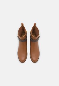 Bottes courtes en cuir marron à finition lisse, dotées d'une bande décorative avec un accent sombre à motifs, fermeture éclair et languettes de traction à l'arrière.