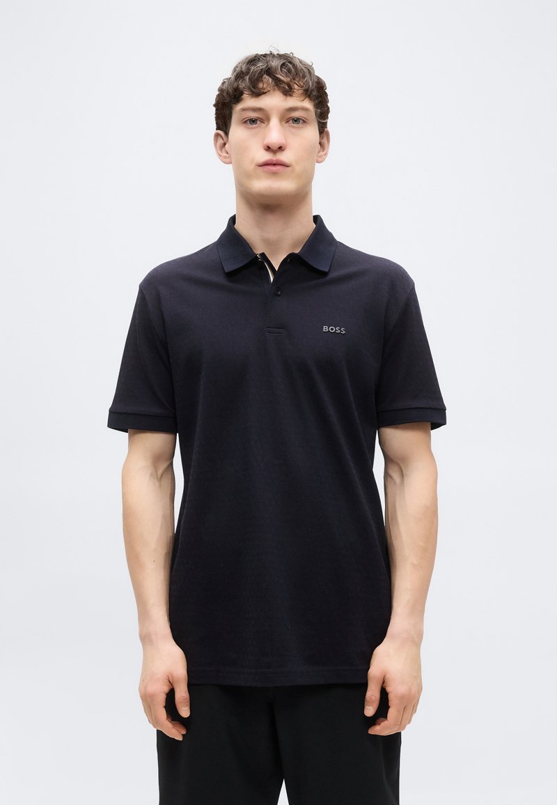 Μαύρο πόλο μπλουζάκι από βαμβάκι με κλασικό γιακά, κουμπιά και κοντά μανίκια. Διαθέτει διακριτικό λογότυπο "BOSS" στο στήθος.