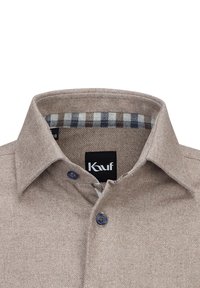 Camicia marrone, con texture e colletto a polo. Presenta una fodera a quadrati blu e bianca, con dettagli di bottoni blu. Etichetta visibile.
