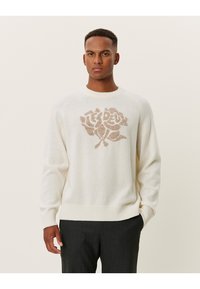 Cremefarbener Strickpullover mit einem großen beigen Rosenmotiv in der Mitte. Verfügt über gerippte Bündchen und Saum, einen runden Ausschnitt und eine weiche Textur.