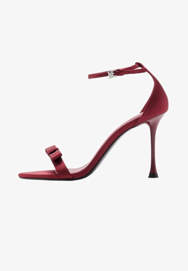 Sandale rouge à talon haut avec fine bride à la cheville, fermeture à boucle, bout ouvert et petit nœud décoratif sur la bride avant.