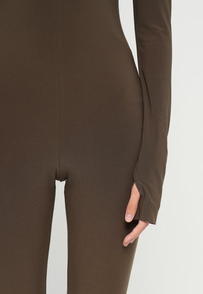 Brown stretch bodysuit with long sleeves, featuring thumbholes and a form-fitting design. Smooth texture and seam detail visible.