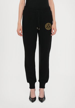 Black sweatpants in soft fabric with an elastic waistband and drawstring. Gold Versace logo on the left thigh. Ribbed ankle cuffs.