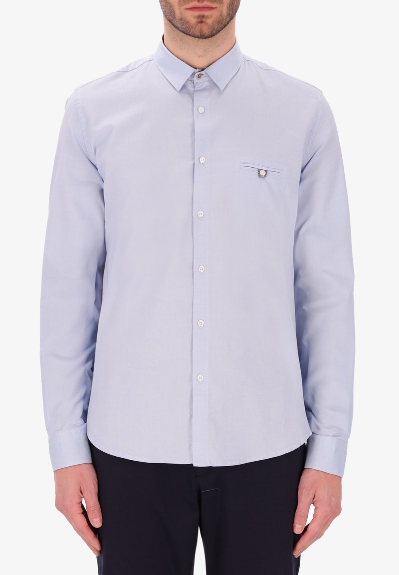 Camicia azzurra a maniche lunghe con colletto a bottoni, tasca frontale e bottoni bianchi. Vestibilità slim, tessuto morbido e orlo curvo.