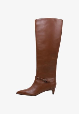 Bota alta hasta la rodilla de cuero marrón, con punta puntiaguda, tacón bajo de tipo kitten y una correa delgada con pequeña hebilla metálica alrededor del tobillo.