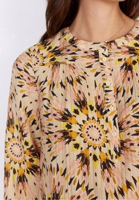 Camicia button-up in tessuto leggero caratterizzata da un motivo floreale multicolore con accenti gialli, rosa e neri; texture a coste.