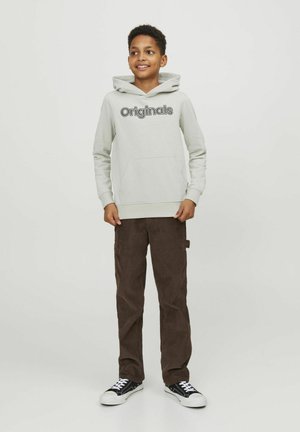 Hellgrau Hoodie mit "Originals" Schriftzug, Fronttasche, kombiniert mit braunen Cordhosen und schwarzen Low-Top Sneakern.