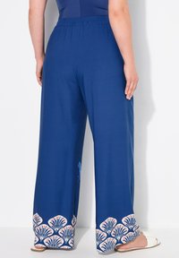 Modré široké kalhoty s elastickým pasem, které mají na lemu dekorativní vzor mušlí v bílé a růžové barvě. Měkká textilie.