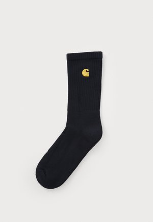 Sorte ribbede sokker med en gul logo på siden. Laget av mykt materiale med en jevn tekstur og en standard crew høyde.