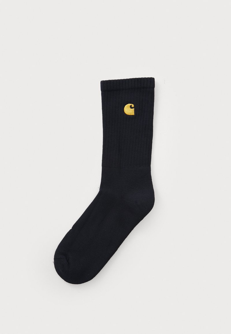 Sorte ribbede strømper med et gult logo på siden. Lavet af blødt materiale med en glat tekstur og en standard crew højde.