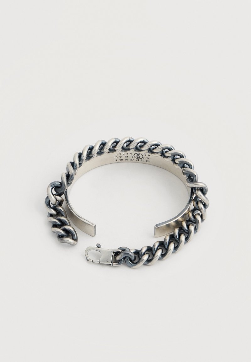 Bracelet chaîne chunky ton argent avec un bracelet ouvert et un fermoir homard, présentant de petits numéros imprimés à l'intérieur du bracelet.