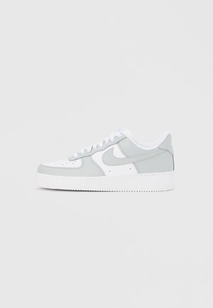 Sneaker Nike Air Force 1 low-top in bianco e grigio chiaro con lacci e logo swoosh distintivo sul lato.