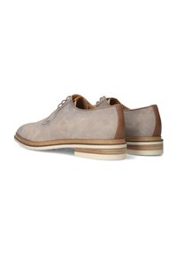 Beige suède schoenen met bruine leren accenten, voorzien van een ronde neus, vetersluiting en een lichte rubberen zool met gelaagde details.
