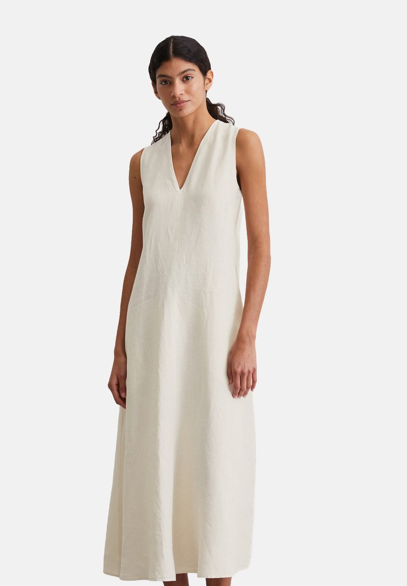 Ärmelloses A-Linien-Kleid aus leichten beigen Leinen mit tiefem V-Ausschnitt und seitlichen Schlitzen, das einen entspannten Schnitt und eine strukturierte Textur aufweist.