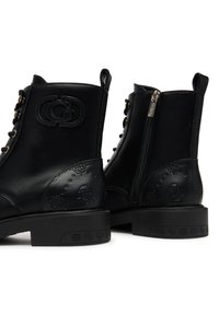 Stivaletti alla caviglia in pelle nera con dettaglio del logo in rilievo, punta tonda, occhielli e chiusura laterale con zip. Suola in gomma piatta con accenti a motivo.