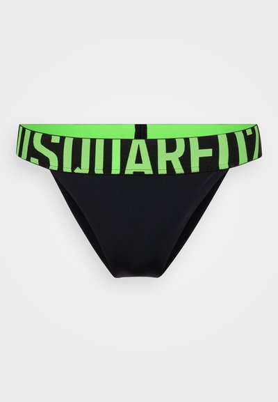 Schwarze Bikini-Unterhose mit einem kontrastierenden grünen elastischen Bund, der auffällige schwarze Buchstaben trägt. Glatte Textur, minimalistisches Design.
