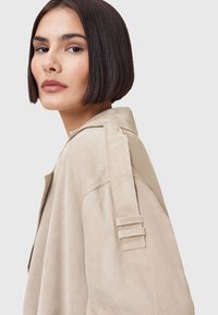 Beige Wildlederjacke mit lässiger Passform, Schulterakzenten und Reverskragen. Verfügt über eine glatte Textur und ein minimalistisches Design.