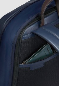 Bolso para portátil de tela azul marino con exterior texturizado, detalles en cuero, un bolsillo con cremallera y una cartera verde visible dentro del compartimento.