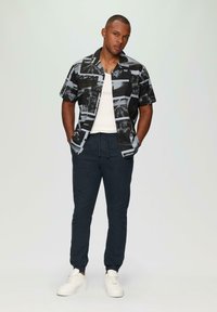 Korte mouwen zwart en grijs gepaard met een navy kleurige drawstring broek en witte sneakers. Schone lijnen en een casual ontwerp.