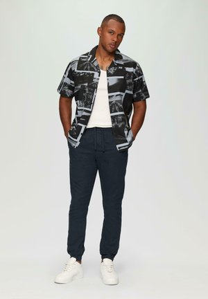 Korte mouwen zwart en grijs gepaard met een navy kleurige drawstring broek en witte sneakers. Schone lijnen en een casual ontwerp.