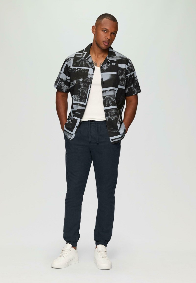 Korte mouwen zwart en grijs gepaard met een navy kleurige drawstring broek en witte sneakers. Schone lijnen en een casual ontwerp.