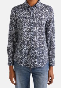 Marinblå skjorta med knappar, med ett vitt och gult blommönster, långa ärmar, krage och rak passform. Tillverkad av mjukt tyg.