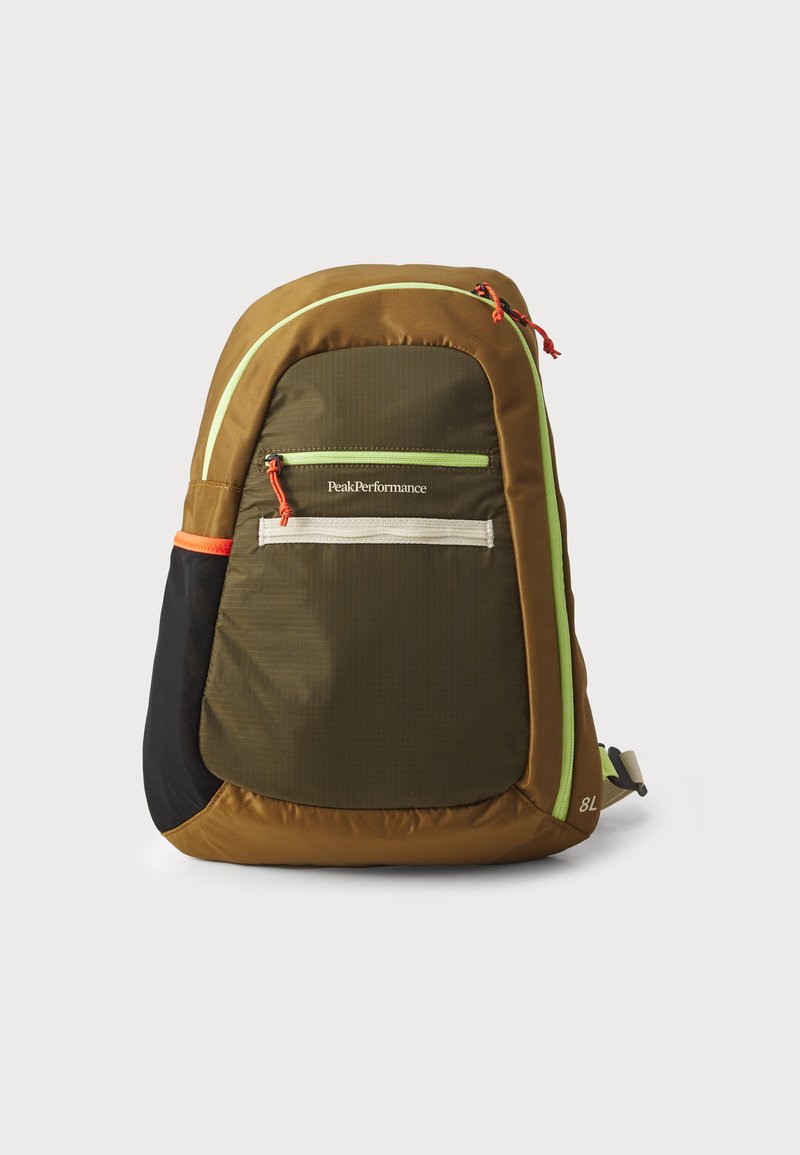 Brown fabric backpack with green accents, featuring a front pocket, adjustable straps, and a mesh side pocket. Brand logo visible.