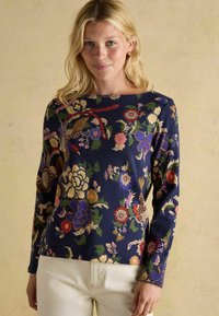 Długa koszula z długim rękawem w granatowym kolorze z kwiatowym nadrukiem, charakteryzująca się żywymi kolorami, złożonymi wzorami oraz dekoltem w łódkę. Gładka tekstura.