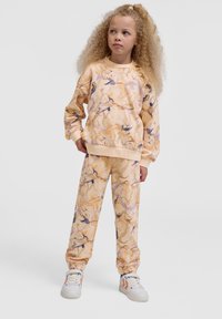 Sweatshirt en sweatpants set in licht perzik met abstracte gouden en paarse patronen, gemaakt van zachte stof. Beschikt over elastische boorden en een elastische tailleband.