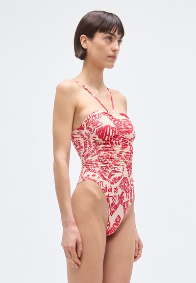Traje de baño de una pieza en rojo y crema con un diseño fruncido, que cuenta con tirantes finos ajustables y un patrón de texto gráfico en toda la superficie. Textura suave.