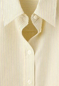 Col de chemise rayé verticalement jaune et blanc avec boutons blancs, ouvert en haut sur un fond rayé assorti.