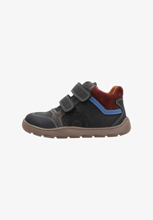 Zapatilla alta negra de tela y sintético con suela marrón, dos tiras ajustables de velcro, detalles en rojo y azul, puntera reforzada y costuras visibles.