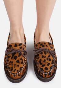 Brune leopardmønstrede slip-on sko med en ruskindsstruktur, lædersnørebånd og en syet kant. Flad gummisål synlig på bunden.
