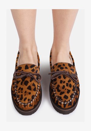 Sapatilhas slip-on de padrão leopardo castanho com textura de camurça, atacadores de couro e um acabamento cosido. Sola plana de borracha visível na parte inferior.