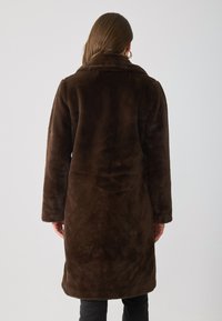 Brown faux fur coat with long sleeves, notched collar, and a straight cut, featuring a soft texture and mid-length design.