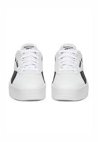 Fehér sportcipők fekete oldalsó csíkokkal, sima bőrfelülettel, perforált orral, lapos fűzőkkel és vastag, strukturált talppal.