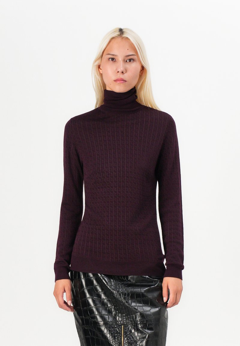 Burgundy turtleneck sweater with ribbed texture and fitted silhouette. Paired with a glossy black crocodile-patterned skirt.