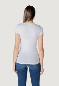 Witte korte mouwen t-shirt met een fitted ontwerp en ronde halslijn, gecombineerd met blauwe denim jeans. Gladde textuur, minimale details.