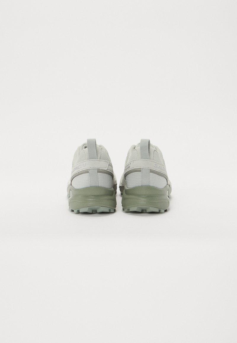 Zapatillas gris y verde claro con un upper texturizado, cuello acolchado y suelas gruesas y resistentes. Cuenta con tiradores para facilitar su uso.