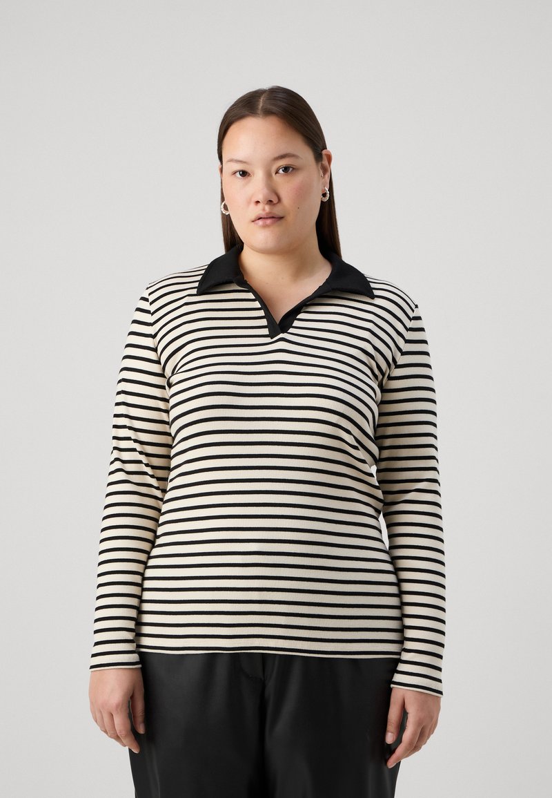 Polo de manga larga a rayas en negro y crema, con cuello negro y tejido texturizado, en una silueta ajustada.