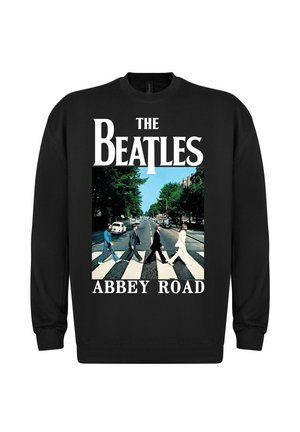 Czarny sweter z napisem "THE BEATLES" i "ABBEY ROAD". Na środku znajduje się grafika przedstawiająca cztery postacie przechodzące przez ulicę, otoczone zielenią.