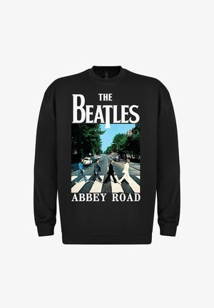 Czarny sweter z napisem "THE BEATLES" i "ABBEY ROAD". Na środku znajduje się grafika przedstawiająca cztery postacie przechodzące przez ulicę, otoczone zielenią.