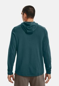 Felpa a maniche lunghe color teal con cappuccio regolabile, dalla texture liscia e polsini a coste. Vestibilità comoda con un design pulito e semplice.