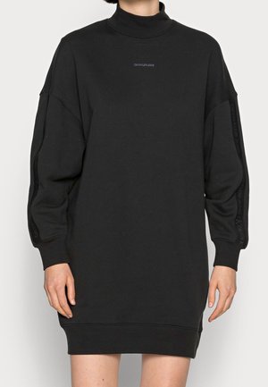Sort oversized sweatshirtkjole med høj hals, tætsiddende ærmer og subtil logo-branding på fronten og ærmerne. Blødt stof. 