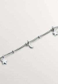 Pulsera de cadena de plata que presenta charms de estrella y luna creciente, con una textura suave y cuentas alternas a lo largo de los eslabones.