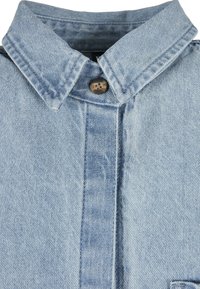 Col de chemise en denim bleu clair avec bouton marron visible et coutures détaillées.